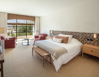 Bright bedroom suite at Villa La Gratitud with garden views, cozy seating, and soft natural tones.