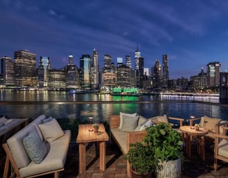 Rooftop lounge with view of New York City skyline at night.