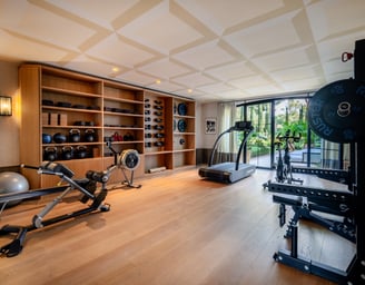 Villa La Gratitud’s gym with full range of fitness equipment, free weights, and garden views