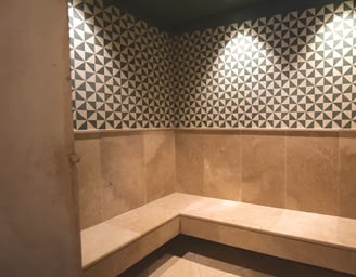 Steam room at Villa La Gratitud’s with geometric tile design and built-in stone bench.