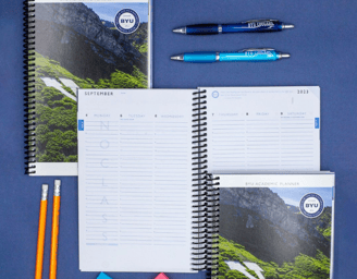 a notebook with a notepad and pens on a blue background