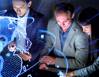 Two female and two male leaders using smart devices in front of a holographic globe