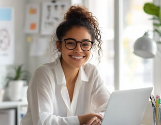 Emprendedora joven sonriente trabajando en laptop, representa productividad y liderazgo femenino en negocio digital en casa.