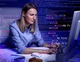 a woman sitting at a computer desk with a laptop