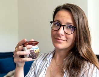 a woman in glasses and a striped shirt is holding a cup of coffee