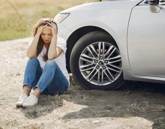 a woman sitting on the ground next to a car