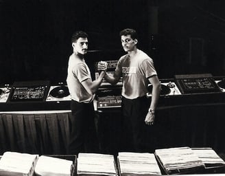 two men standing in front of a table with records