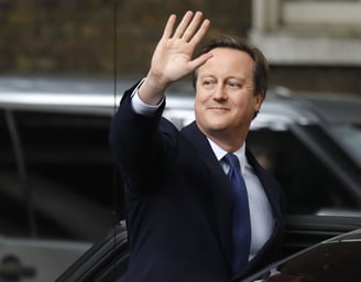 David Cameron in a suit and tie is waving his hand