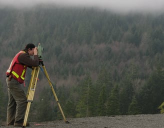 a man in a red vest and a yellow vest is holding a tripod