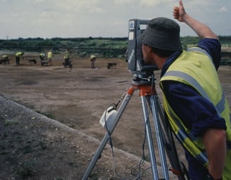 a man in a yellow vest and a camera on a tripod