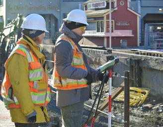 two men in safety vests standing in front of a building