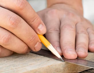 gros plan main traçant une planche de bois