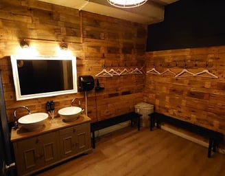A male changing room from a private gym facility in east London. There is a sink, mirror and benches