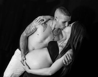 photo de grossesse avec un couple s'embrassant sur fond noir