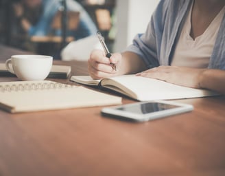 woman at a desk with notebook and coffee cup