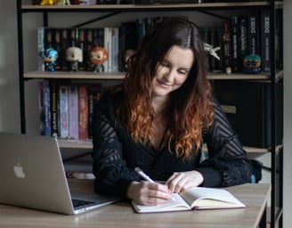 une femme assise prenant des notes avec un ordinateur