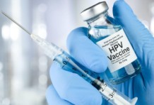 a person in gloves holding a HPV vaccine and a syringe