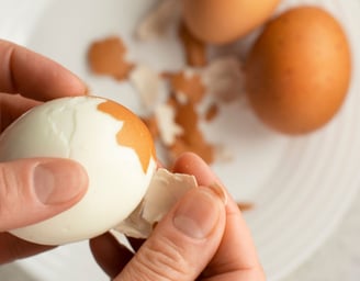 someone peeling a hard boiled egg