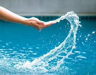 Close-up of a hand gracefully touching splashing water in a clear blue pool, symbolizing attentive and hands-on pool service.