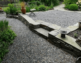 a garden with a stone wall and a statue of a lion