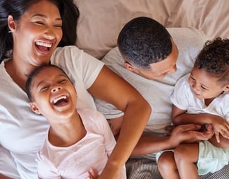 playful family members cuddle and wrestle in bed