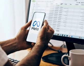 a man holding a phone in front of a computer screen