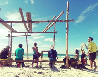 groupe de personne de dos jouant des tambours sur une plage