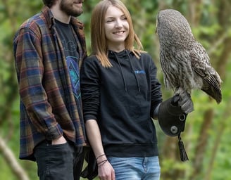 a man and woman standing next to each other with a bird of prey