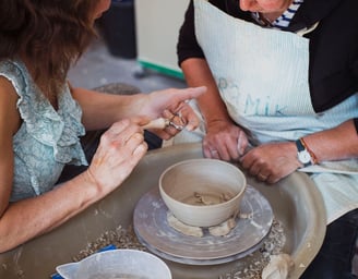 Two people around a potters wheel making a bowl