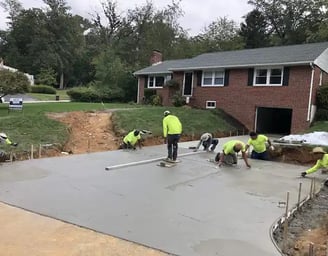 a group of men in yellow jackets and yellow jackets working on a concrete slab