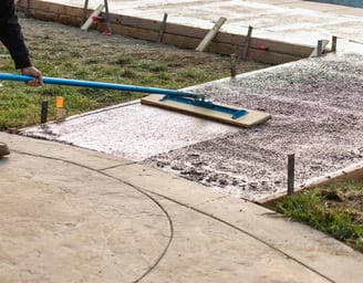 a person using a broom to clean a sidewalk