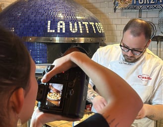 a man is taking a picture of a pizza