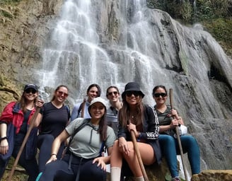 a group of people standing around a waterfall