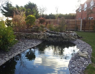 a pond with rockery stone and water in the foreground