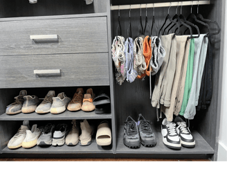 Organized closet with folded shorts, hanging pants, and neatly arranged sneakers and shoes.