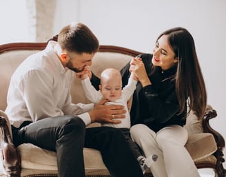 a man and woman sitting on a couch with a baby