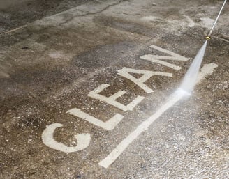 Clean written on to a concrete walk way by a pressure washing services pressure washing worker