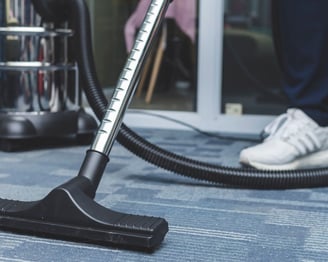 a person is cleaning a carpet with a vacuum