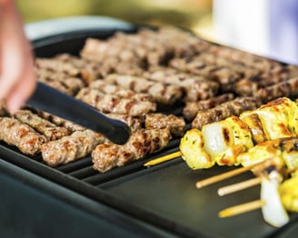 a person is cooking on a grill with skewers
