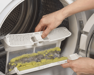 a person is putting a plastic container into a washing machine