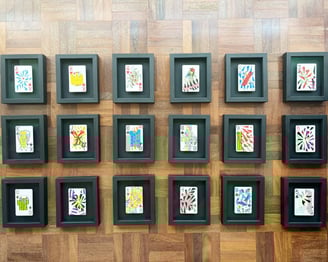 vista de cima das 18 cartas de baralho personalizadas e colecionáveis da série, emolduradas em preto sobre chão de taco.