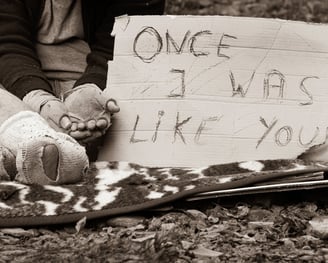 a person sitting on a blanket with a sign that says one of the signs