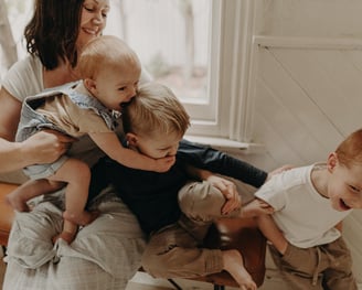 a woman holding a baby and two children