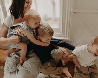 a woman holding a baby and two children