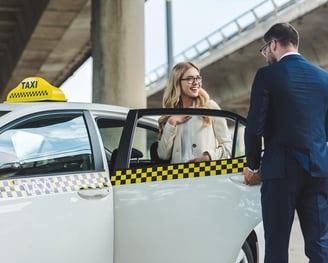 un chauffeur de taxi ouvre la porte de taxi pour une cliente souriante