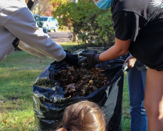 Group of young adult volunteers bagging leaves.