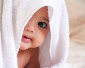 Bébé couché sur le ventre avec une serviette blanche sur la tête - Micro crèche Martinique