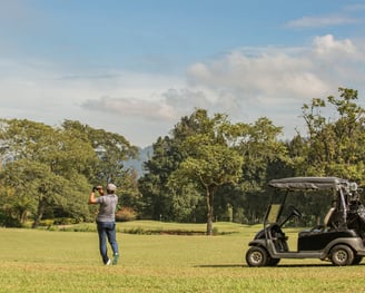 a man standing in a field with a golf carton