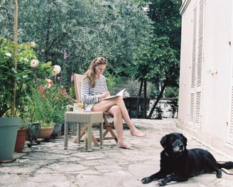 photo de l'artiste sur une chaise en train de peindre dans un jardin avec son chien