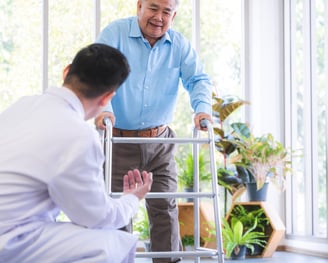 a Physiotherapist in a white shirt and a man in a blue shirt and a walker